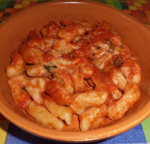 Pasta fresca fatta in casa condita con pomodoro e mozzarella filante al forno