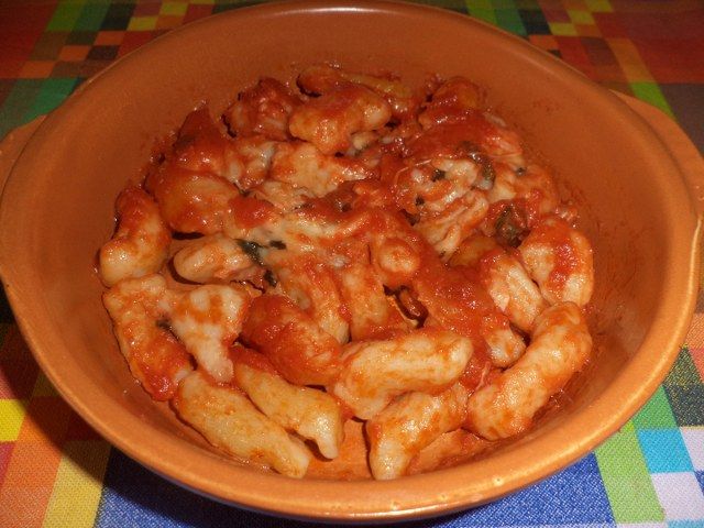 Pasta fresca fatta in casa condita con pomodoro e mozzarella filante al forno